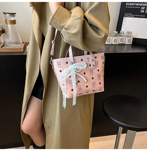 Détail du mini sac seau rose clair avec nœud en dentelle et breloque perle motif croisé