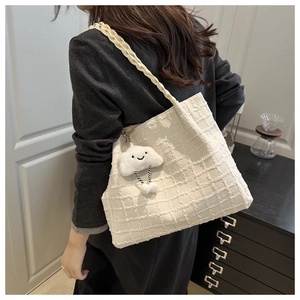 Detail of off-white tweed tote bag with woven shoulder strap and cloud charm pendant