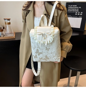 Détail du sac à dos en similicuir crème avec bordure en dentelle, nœud et perle