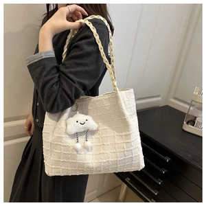 Close-up of white tweed tote bag with woven texture and cute cloud plush charm