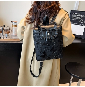 Détail du sac à dos noir avec broderie papillon et pendentif nœud orné d'une perle
