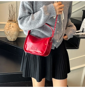 Close-up of red glossy leather handbag featuring textured pleats and Fashion label detail