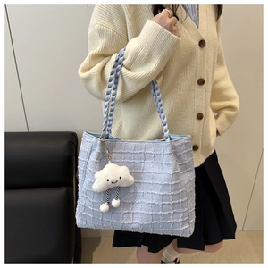 Close-up of light blue tweed tote bag texture with woven rope handle and cloud charm