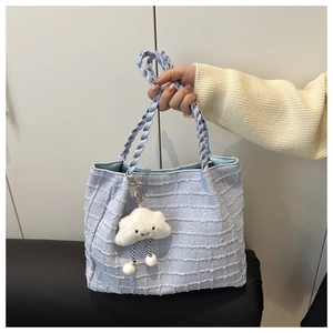 Close-up of light blue tweed tote bag texture with cute white cloud plush pendant