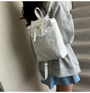 Détail du sac à dos blanc avec relief papillon, dentelle délicate et nœud en perles