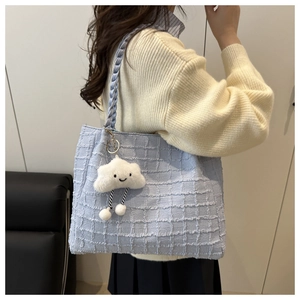 Detail of light blue tweed tote bag with woven strap and fluffy white cloud pendant