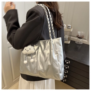 Detail of silver quilted tote bag with woven shoulder straps and cloud plush charm