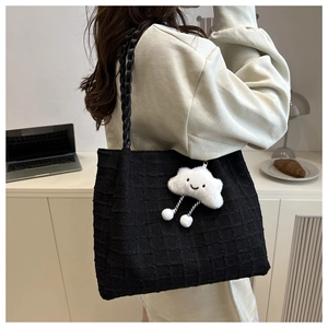Detail of black pleated tote bag featuring a cute white plush cloud charm for daily use