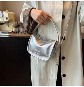 Close-up of metallic silver handbag with Fashion plaque and chain strap detail
