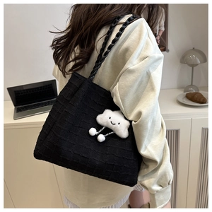 Detail of black textured tote bag with cute white cloud charm and woven shoulder strap