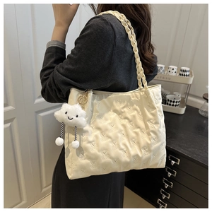 Detail of cream white tote bag featuring embossed bear patterns and a plush cloud charm