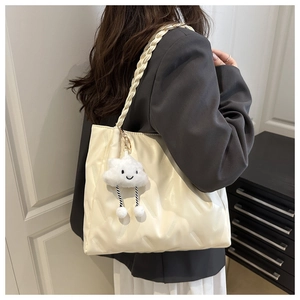 Detail of cream quilted tote bag with woven shoulder strap and cute cloud charm pendant