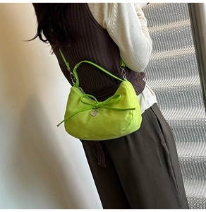 Dettaglio borsa dumpling in camoscio verde lime con fiocco in pelle e ciondolo cuore