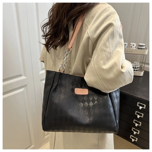 Detail of black quilted leather tote bag featuring pink logo and chain strap accents