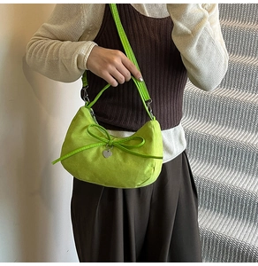 Dettaglio della borsa a spalla in camoscio verde brillante con fiocco e cuore in argento