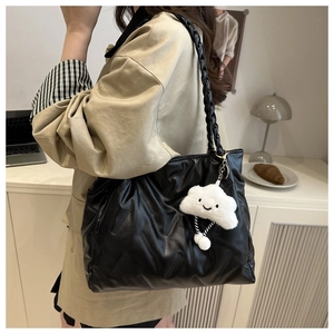 Detail of black quilted shoulder bag with white plush cloud charm on a casual setting