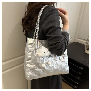 Detail of silver tote bag featuring embossed bear patterns and a white cloud plush charm
