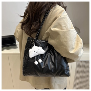 Quilted leather tote bag with woven handle and plush cloud charm on model's shoulder