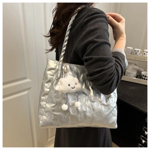 Detail of silver quilted tote bag with bear pattern and plush cloud smiley pendant