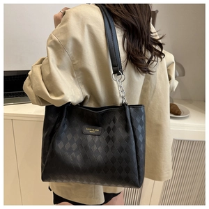 Detail of black leather tote bag with diamond quilted pattern and silver chain handle