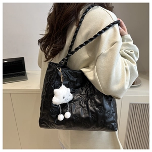 Detail of black bear-patterned quilted tote bag with a white cloud plush charm and rope straps
