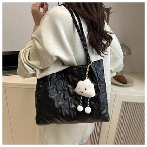 Detail of black tote bag with bear embossing and a white cloud plush charm accessory