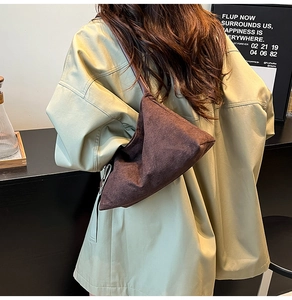 Detail of brown suede shoulder bag showing triangular design and wide strap on model