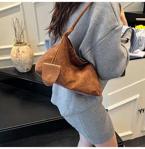 Detailed close-up of dark brown suede hobo bag featuring a soft texture and matching charm