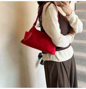 Detail of red suede underarm bag showing the knot strap and minimalist rectangle shape