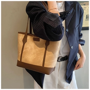 Detail of a large brown tote bag with FASHION logo and wide straps for commuting