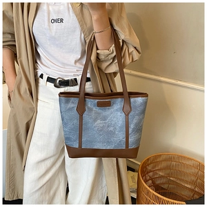 Detail of the blue marbled canvas tote bag with brown leather trim and fashion tag