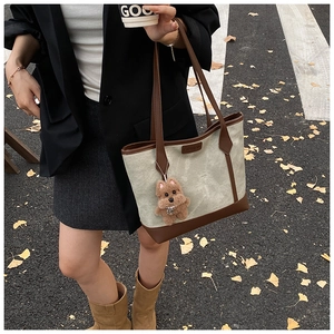 Chic tote bag with teddy bear charm shown in a stylish autumn street scene setting