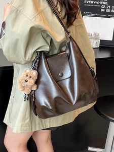 Brown large capacity leather shoulder bag with plush bear charm and vintage buckle closure