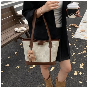 Canvas tote bag with leather trim and cute puppy charm in a scenic outdoor park setting