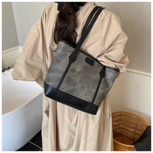 Fashion large capacity tote bag with grey texture and black leather straps on a model