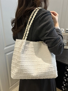 White tweed tote bag with woven rope straps shown on model in a casual home setting
