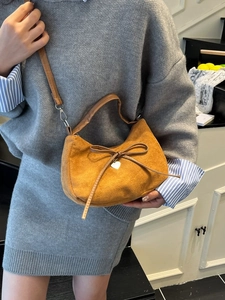 Borsa a mezzaluna in camoscio marrone con fiocco e ciondolo a cuore su una modella