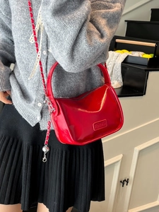 Glossy red crossbody bag with silver chain strap and top handle in a trendy style