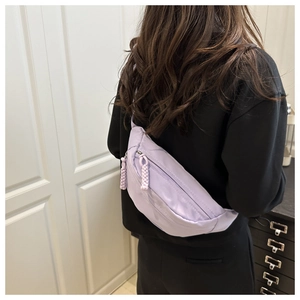 Detail view of a lavender canvas crossbody saddle bag worn on a model's back