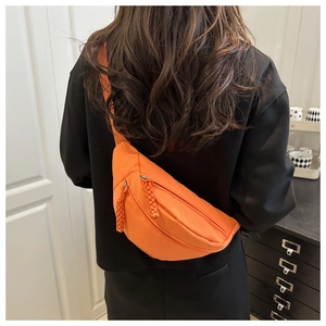 Detailed back view of a bright orange crossbody chest bag worn over a black hoodie