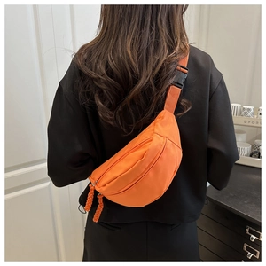 Detail of orange nylon dumpling bag with woven zipper pull and adjustable black buckle strap