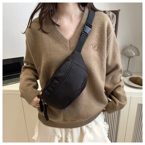 Detail of black crossbody chest bag with adjustable strap and plastic buckle closure