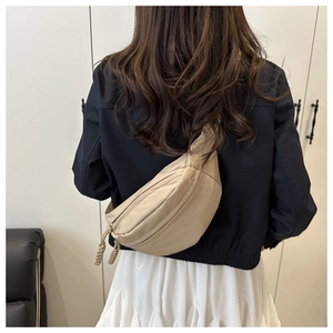 Detail view of beige crossbody chest bag with woven zipper pull and durable fabric texture
