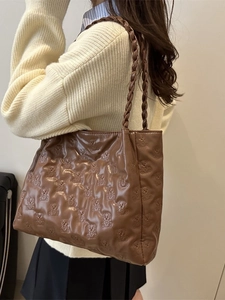 Brown faux leather tote bag with embossed bear patterns and woven handles shown on a shoulder