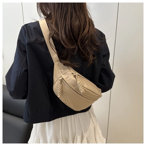 Detail of a beige nylon crossbody chest bag with moon shape and woven zipper pullers