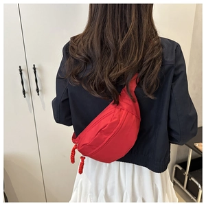 Detailed view of red nylon waist bag with durable zip closure and woven puller on model