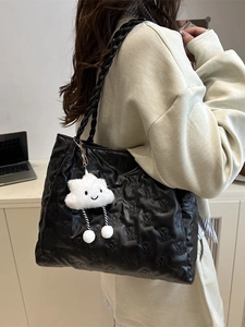 Minimalist black tote bag with embossed bear pattern and plush charm on shoulder