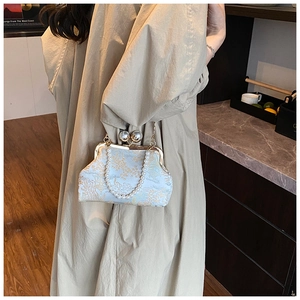 Close-up of light blue floral jacquard clutch bag with oversized pearl clasp and chain