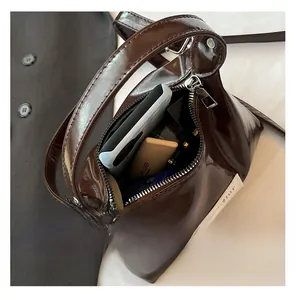 Detail view of large capacity dark brown patent leather bag with daily essentials inside