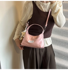 Close-up of pink patent leather handbag featuring a cute brown plush bear charm